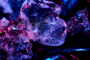 close up view of transparent ice cubes with purple illumination isolated on black