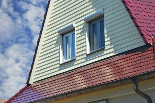 Gelb gestrichene Holzschindel-Verschalung des Dachgeschosses eines renovierten Fachwerkhauses