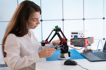 A young woman writes an algorithm for the robot arm. Science Research Laboratory for Robotic Arm Model. Computer Laboratory