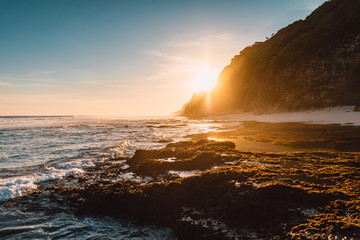Beach with ocean waves and sunshine light at sunset or sunrise