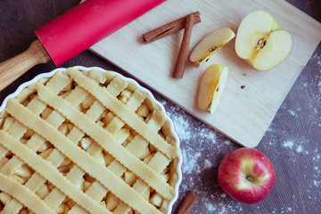 Traditional homemade apple pie and ingredients on wooden background for autumn holiday