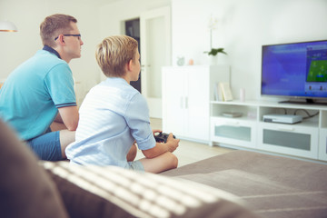 Fototapeta premium Happy young father and his son playing computer games with controllers very emotional