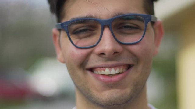 Portrait of attractive young man teenager looking at camera and smiling. Blue glasses.