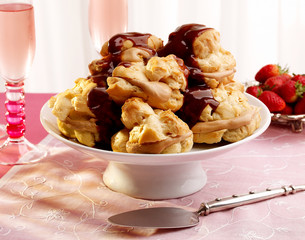 Chocolate & Caramel Profiteroles on stand with serving implament.