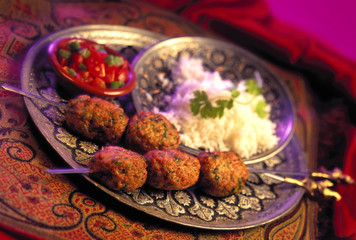 Indian Spicy Meat Balls on skewers.  Placed on brass plate with rice and sambals.