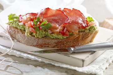 Bacon & Mashed Avocardo on Crusty Bread in a rustic setting