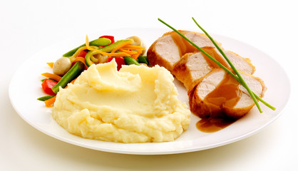 Sliced Chicken in Gravy with Vegetables and Mash. Plated against a white background