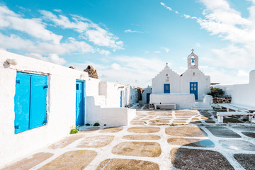 Mykonos, Greece - 01 22 2019 – Greek white church with blue colors at the cobbled alleys of...