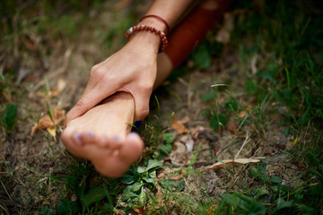 Close up of woman holding leg. Practicing yoga in nature concept.