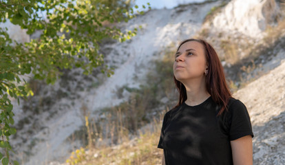 A beautiful young woman in black clothes against the white chalk mountains.