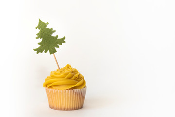 Fresh yellow cupcake with the Christmas tree isolated on white background. Celebrative composition, holiday concept, copy space
