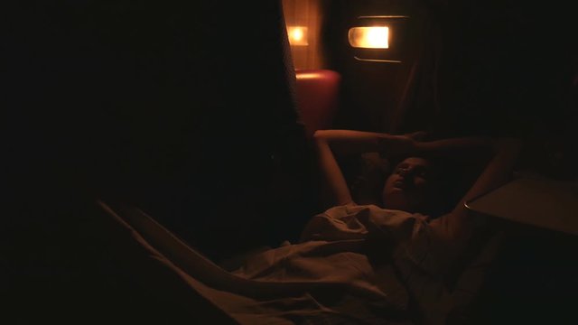 Bad dream girl sleep in train. Night time international trip, dark outdoors and few lights seen outside. Very dark in a train car.
