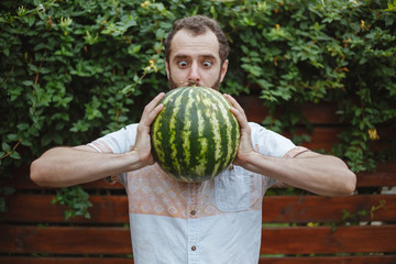 Fototapeta premium Photo shocked surprised young handsome boy with a watermelon in his hands.