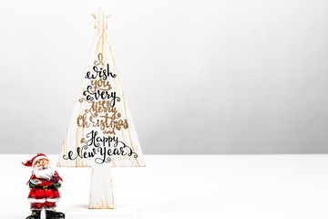Beautiful Minimal Christmas wood tree with Merry Christmass and happy new year written, with small Santa Claus, on white backgound