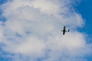 Small airplane flying in the sky with clouds
