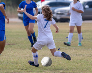Young girl athlete playing soccer on a hot day