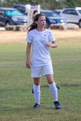 Young girl athlete playing soccer on a hot day