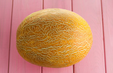 Ripe yellow melon on a pink painted background. Selective focus.