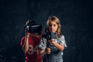 Little boy has fun wearing vr goggles while girl is making selfie by mobile phone.