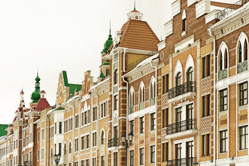 Fototapeta premium Fragment of a building wall with windows, orange kripich and white marble, Yoshkar-Ola, Russia, Brown color