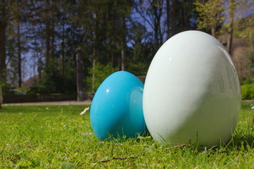 A blue and a white easter egg in the park