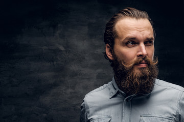 Fototapeta premium Groomed bearded man in light shirt is posing at dark photo studio.
