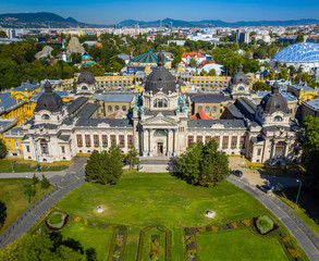 Obraz premium Budapest, Hungary - Aerial drone view of the famous Szechenyi Thermal Bath in City Park (Varosliget) on a sunny summer day with clear blue sky and green trees