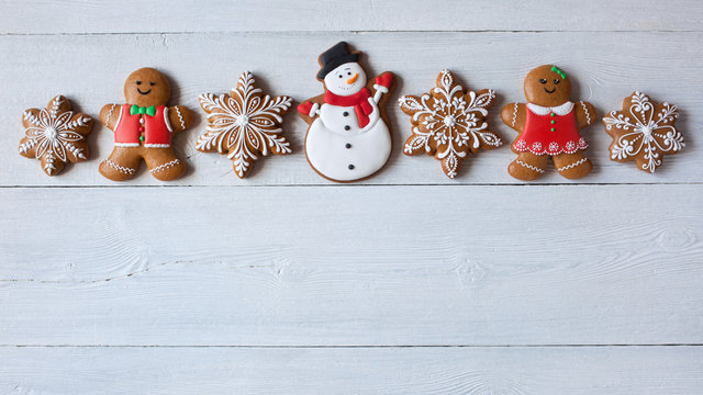 Christmas wooden background with gingerbread snowflakes, gingerbread men and snowman.