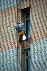 industrial climber descending a rope along the facade of a brick house