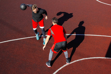 Movement and moment of the dribbling on the basketball court during the match. Athletic lifestyle and basketball competitions. Two young athletes play basketball. Basketball hoop defense and attack.