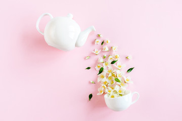 Creative layout of teapot and tea Cup with Jasmine flowers on a pink background. Jasmine tea.