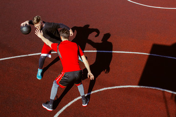 Two young basketball players are fighting for possession of the ball. Top view of a basketball game of two athletes on the court. Competitions and sports match. Defense and attack in basketball.