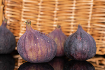 Fototapeta premium Group of four whole fresh fig fruit with braided rattan behind