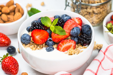 Greek yogurt granola with fresh berries on white table.