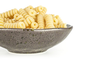 Lot of whole fresh raw pasta fusilli bucati on grey ceramic plate isolated on white background