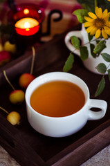 A cup of green tea and apples on the wooden trey on the table. Green tea in the white cup for breakfast. An autumn morning with green tea for breakfast in a cozy home.