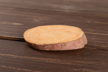 One slice of fresh brown sweet potato on brown wood