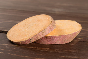 Group of two slices of fresh brown sweet potato on brown wood