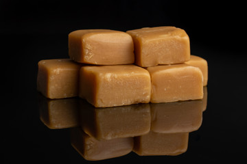 Lot of whole sweet golden caramel candy isolated on black glass