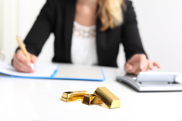 Frau mit Goldbarren und Taschenrechner