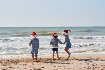 Happy Little children travelers in Santa hats having fun on tropical beach. Christmas and new year holiday vacation concept.  © oes