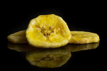 Group of three slices of sweet yellow dry banana isolated on black glass