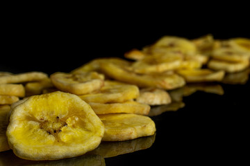 Lot of slices of sweet yellow dry banana placed diagonally isolated on black glass