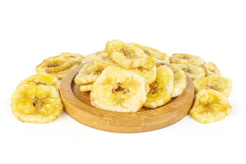 Lot of slices of sweet yellow dry banana on bamboo coaster isolated on white background