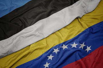 waving colorful flag of venezuela and national flag of estonia.