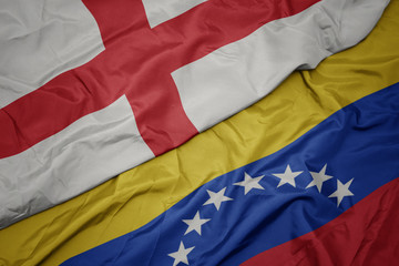 waving colorful flag of venezuela and national flag of england.
