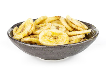 Lot of slices of sweet yellow dry banana in dark ceramic bowl isolated on white background
