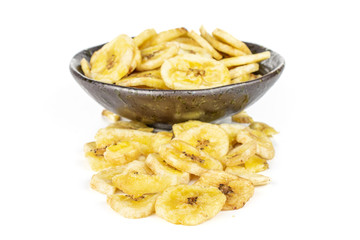Lot of slices of sweet yellow dry banana in dark ceramic bowl isolated on white background