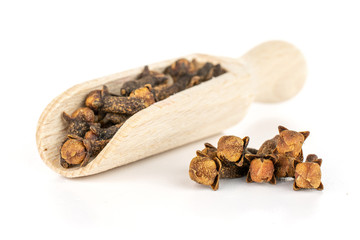 Lot of whole dry brown clove in a wooden scoop isolated on white background