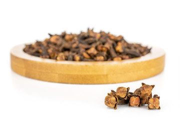 Lot of whole dry brown clove on bamboo coaster isolated on white background